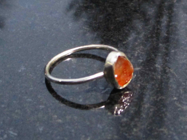 A handmade US size 6.5 fire opal silver stacking ring made with a rough oval sha